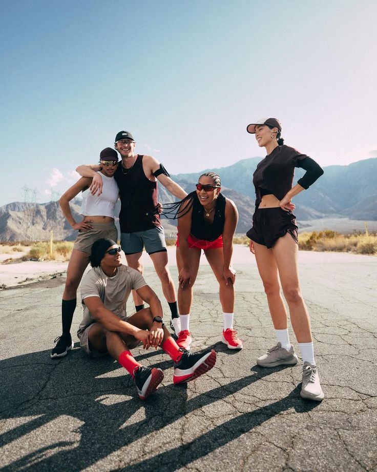 A crew of runners posed together on an open desert road