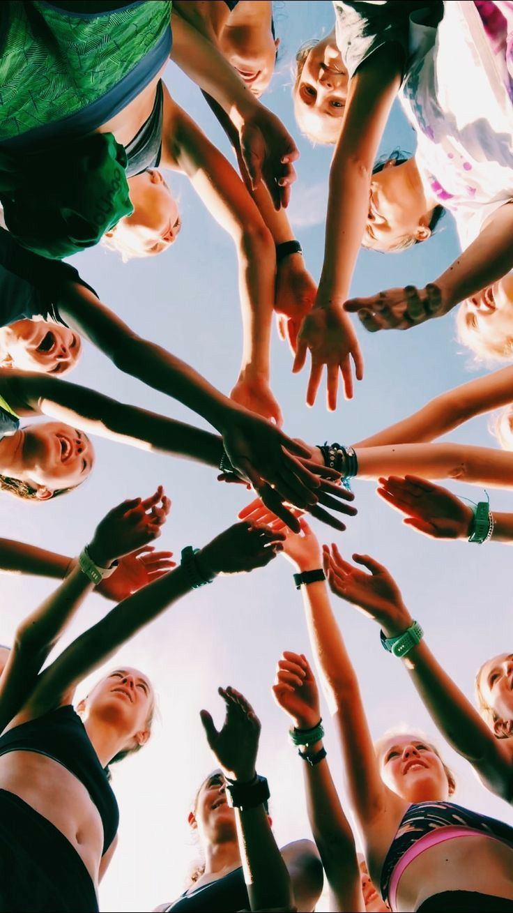 Hands stacked together in a circle against the sky