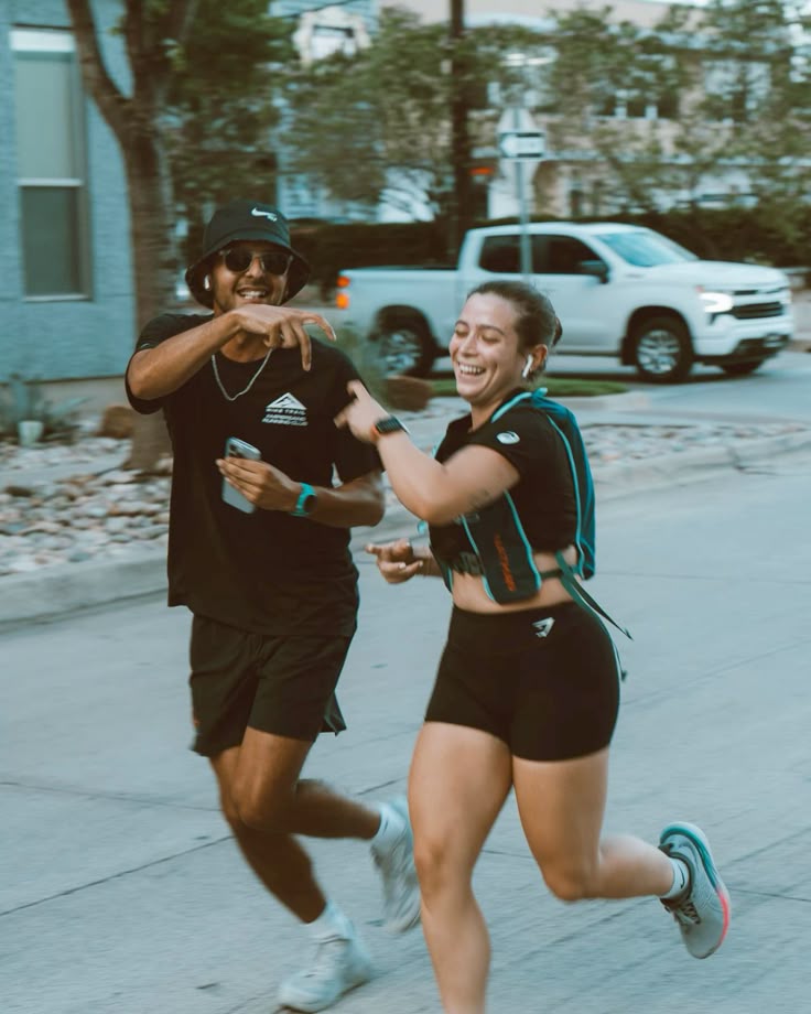 Two runners laughing together mid-run on a sunny street